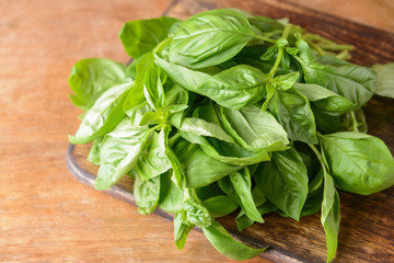 Cutting board with fresh green basil on wooden table