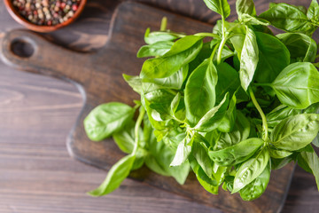 Board with fresh green basil on wooden table, top view