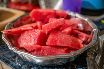Slices of watermelon lie in a metal plate on a marble table close-up