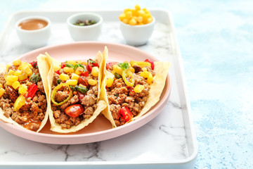 Plate with tasty fresh tacos on light color background
