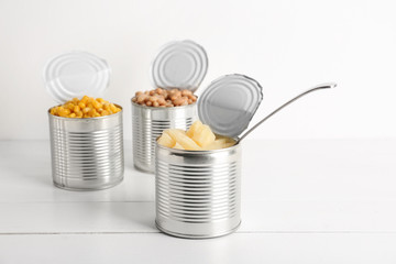 Tin cans with different food on white wooden table