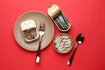 Tin cans with sprats in oil on color background