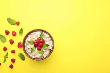 Bowl with tasty sweet oatmeal and raspberry on color background