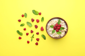 Bowl with tasty sweet oatmeal and raspberry on color background