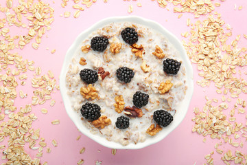 Bowl with tasty sweet oatmeal on color background