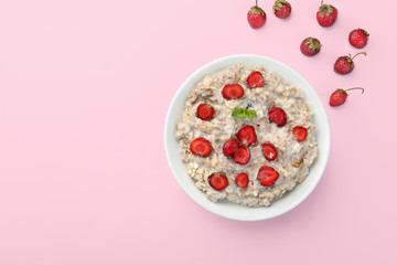 Bowl with tasty sweet oatmeal on color background