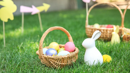 Basket with Easter eggs and bunny on grass outdoors