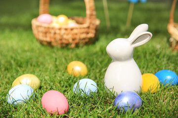 Easter eggs with ceramic bunny on grass outdoors