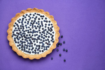 Tasty bilberry pie on color background