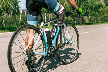 Naklejka premium Athlete with disabilities or amputee training in cycling in sunny summer's day. Professional male sportsman with leg prosthesis practicing outdoors. Disabled sport and healthy lifestyle concept.