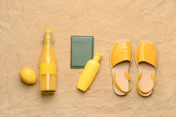 Sandals, juice, passport and cosmetics on sand