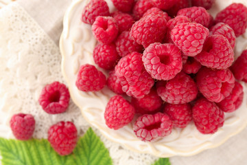 Plate with sweet ripe raspberry on table