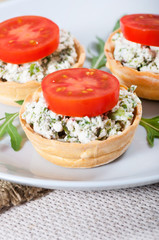 Cottage cheese with greens and tomato on a wooden background.