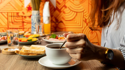 Breakfast on the table is bacon, fried egg, coffee, tea, bread.