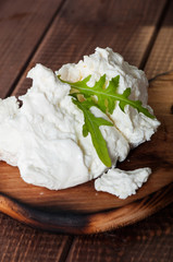 Cottage cheese on the old wooden background, decorated with arugula.