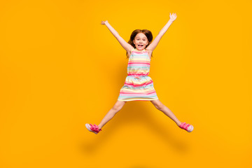 Fototapeta na wymiar Full size photo of pretty child jumping raising hands isolated over yellow background