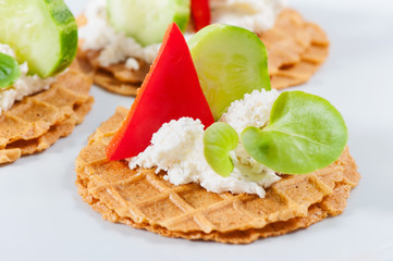 Salty waffles with cheese, herbs, sweet red pepper, cucumber on a light background.