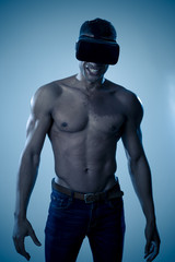Fototapeta na wymiar Strong sports young man with muscular body wearing Virtual Reality headset