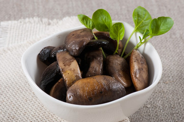 Grilled champignons in a white plate on a fabric background.