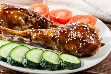 Grilled chicken with teriyaki sauce and vegetables on an old wooden background.