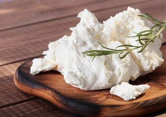 Cottage cheese on old wooden background, decorated with a sprig of rosemary.