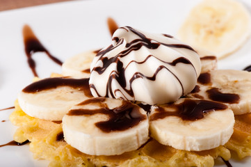 Sweet waffles with banana slices poured with chocolate sauce.