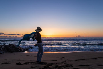 Fototapeta na wymiar Silhouette of young girl with hat, at sunset on Cotillo beach, Fuerteventura, Canary Islands, Spain.