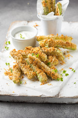 Zucchini sticks in breadcrumbs, with cheese, herbs, breadcrumbs and white yogurt sauce. Healthy snack, summer food