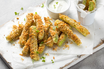 Zucchini sticks in breadcrumbs, with cheese, herbs, breadcrumbs and white yogurt sauce. Healthy snack, summer food