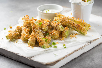 Zucchini sticks in breadcrumbs, with cheese, herbs, breadcrumbs and white yogurt sauce. Healthy snack, summer food