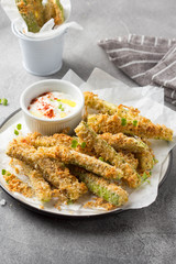 Zucchini sticks in breadcrumbs, with cheese, herbs, breadcrumbs and white yogurt sauce. Healthy snack, summer food