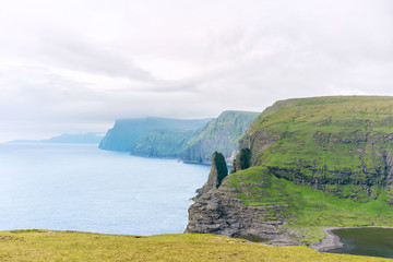 Picturesque Vagar island panorama shoot at Sorvagsvatn/Leitisvatn lake with green rocks, Atlantic Ocean and great clouds. Faroe Islands.