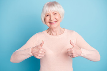 Portrait of cheerful lady showing thumb up smiling wearing paste jumper isolated over blue background