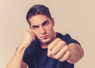 Young attractive man with an angry face in boxing stance ready to fight