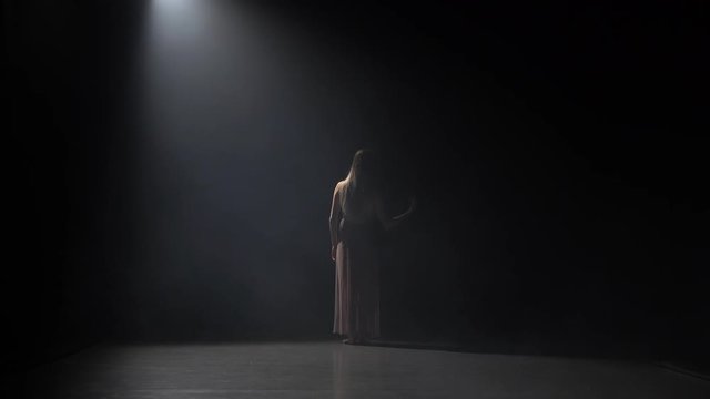 Motion of a skillful maiden dancing contemporary in dark studio.