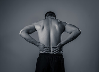 Strong young man suffering lower back pain in stress and bad posture