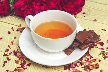 Cup of green tea on table with fresh peony flowers