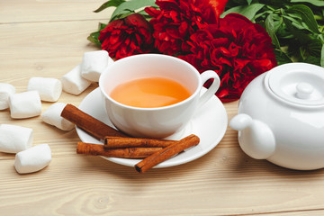 Cup of green tea on table with fresh peony flowers
