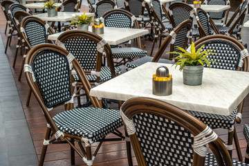 Restaurant table and chairs settings in outdoor dinning area  Elegant chair with stylish marble surface tabletop. Green plants in pot placed on table.