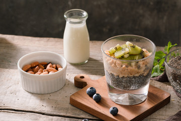 Healthy breakfast - bowl of muesli, berries and fruit, nuts, kiwi, milk