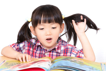 白背景の前で絵本を読む幼い女の子。幼児、教育、読書、学習、成長、育児イメージ