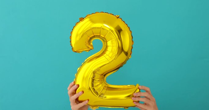 Gold foil number 2 celebration balloon on a blue background