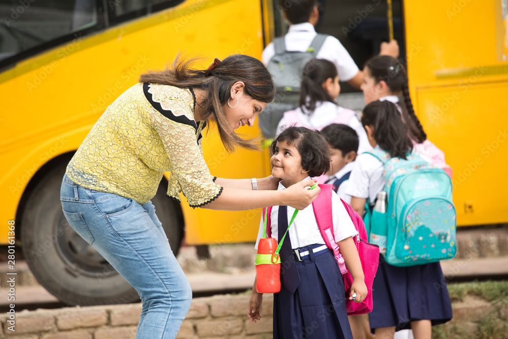 Sticker happy teacher and schoolgirl interacting in front of school bus