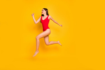 Fototapeta na wymiar Full body profile photo of funny lady jumping high seaside sportive competitions champion speed jogging wear red swim suit isolated yellow background