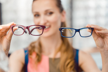Woman choosing between two models of glasses at optometrist