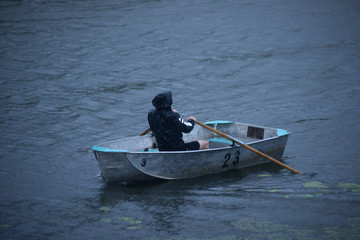 Man rowing boat in the rain in the evening