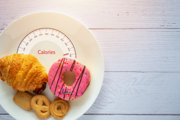 Calories counting and food control concept. doughnut ,croissant and cookies on white plate with...