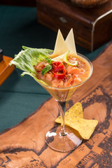 salmon snack or tartar with chili pepper and nachos in martini glass on old map background