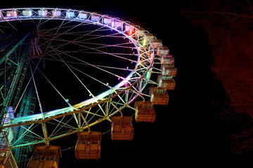 Part of ferris wheel with multicolor lighting at night.