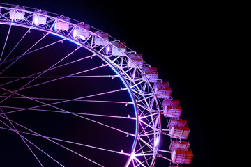 Part of ferris wheel with purple lighting at night